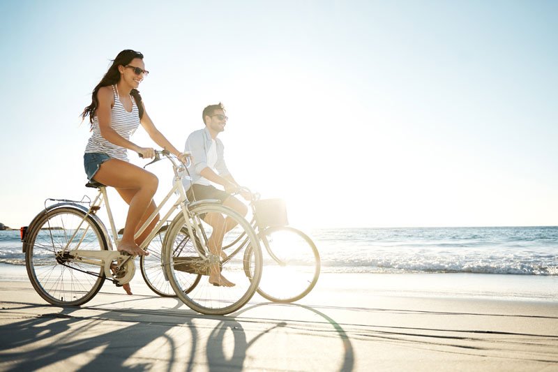 Ehe auf Urlaub. Ein Paar fährt mit Fahrrädern am Strand.